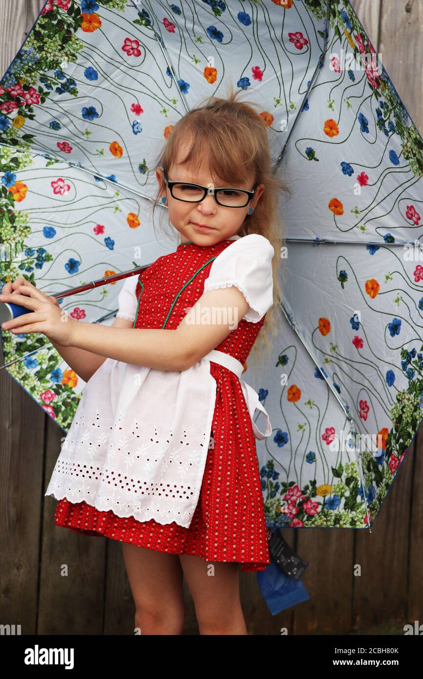 Child in Bavarian dirndl holding an umbrella Stock Photo