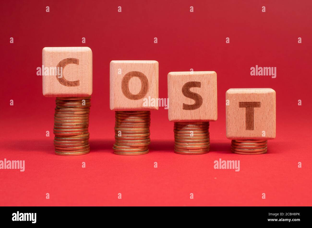 COST word made with wooden blocks with stacked coins: Cost reduction Stock Photo