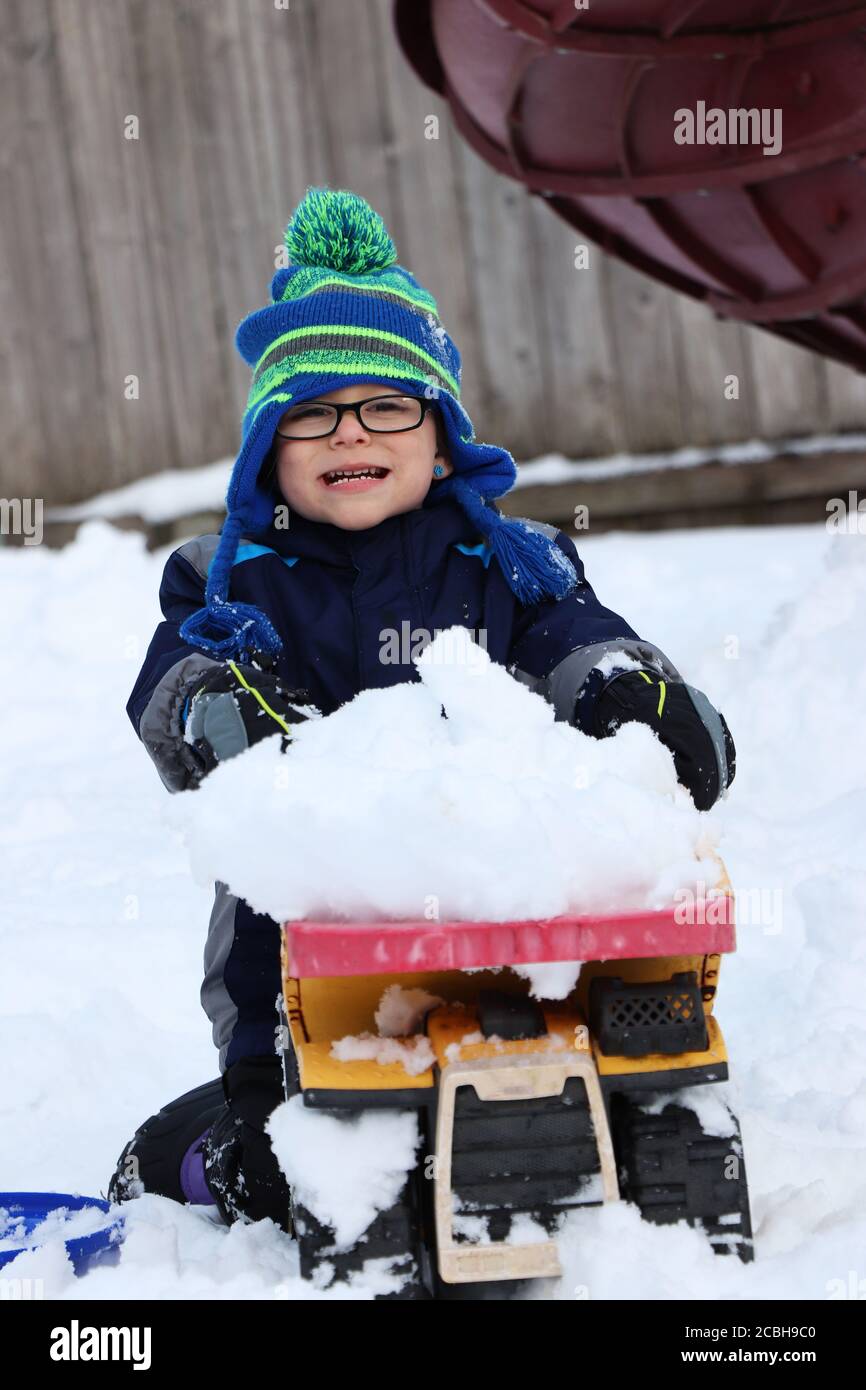 Child playing with toy truck in snow Stock Photo