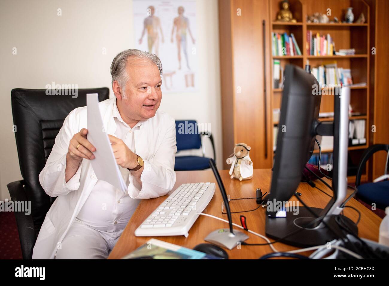 Freising, Germany. 06th Aug, 2020. Dr. Wilhelm Schröttle, family doctor and  specialist for internal medicine, manual medicine and acupuncture, talks to  a reporter in his practice via a video call in front