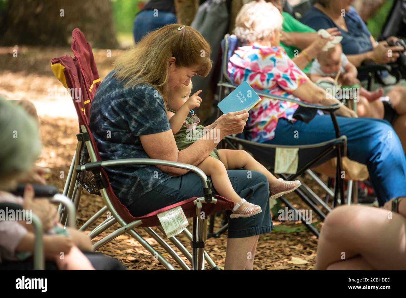 Woman reading to a young toddler at a family reunion picnic along the bank of the Chattahoochee River in Helen, Georgia. (USA) Stock Photo