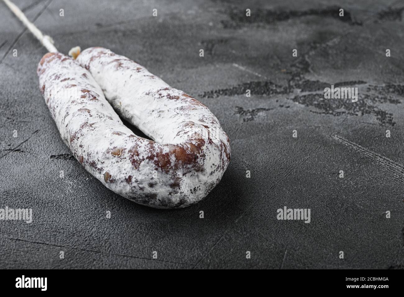 Dry cure salami sausage fuet on grey textured background with copy