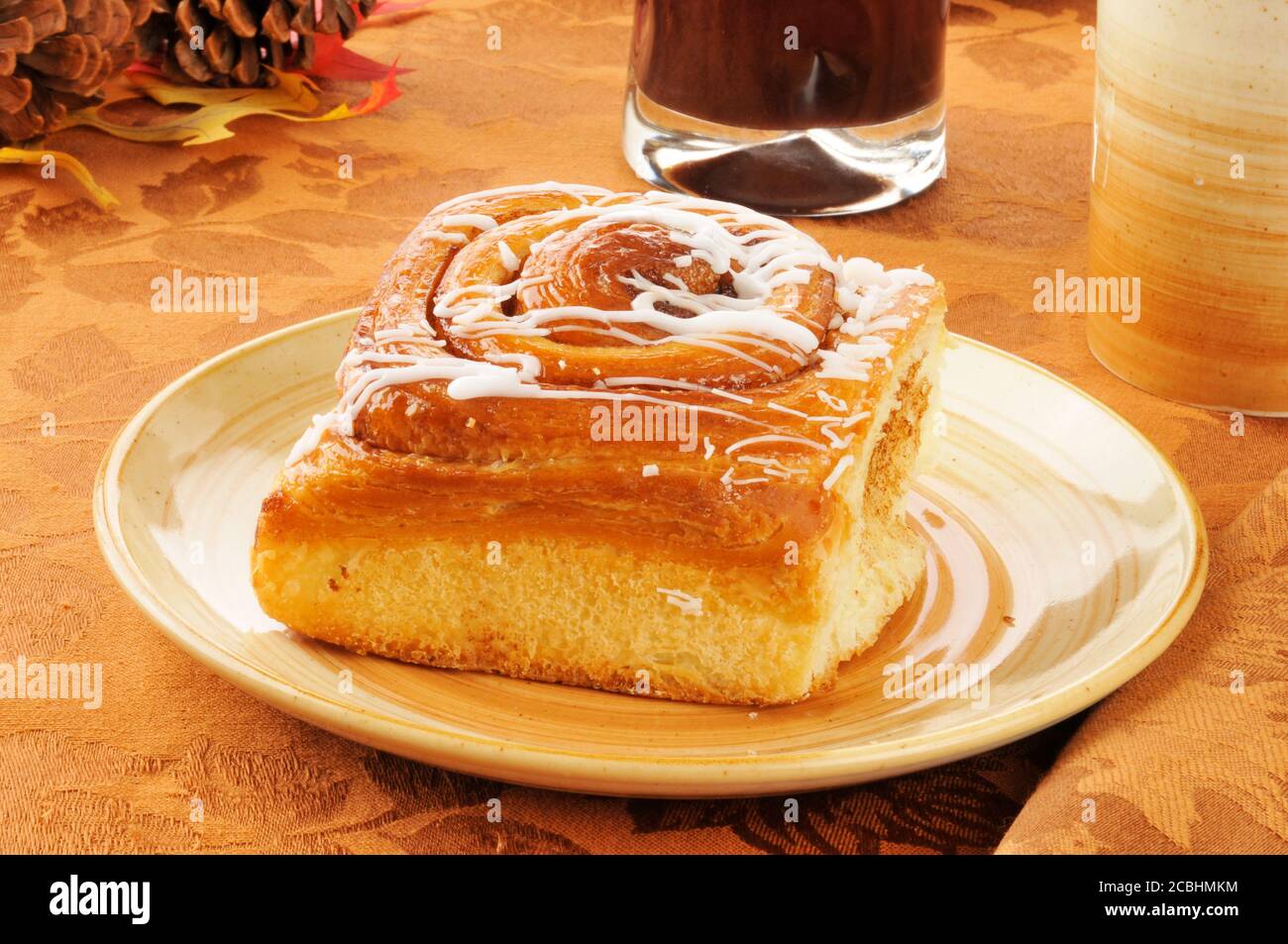 A cinammon roll with a cup of coffee and a glass of juice Stock Photo