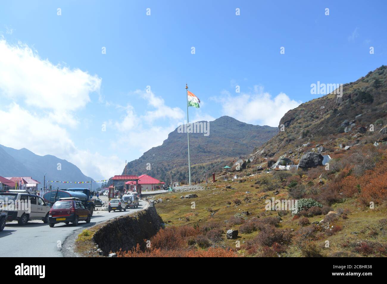 Cars lined up near Baba Harbhajan Singh Sahib Mandir in Nathu La with Indian Flag flying high, selective focusing Stock Photo