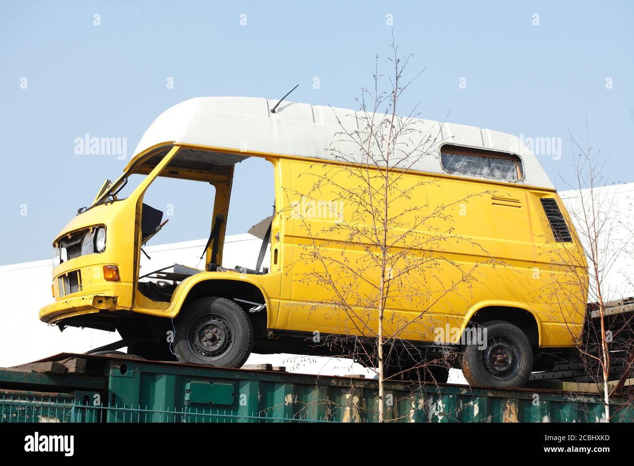 Yellow VW bus post bus on a scrap yard, Germany Stock Photo