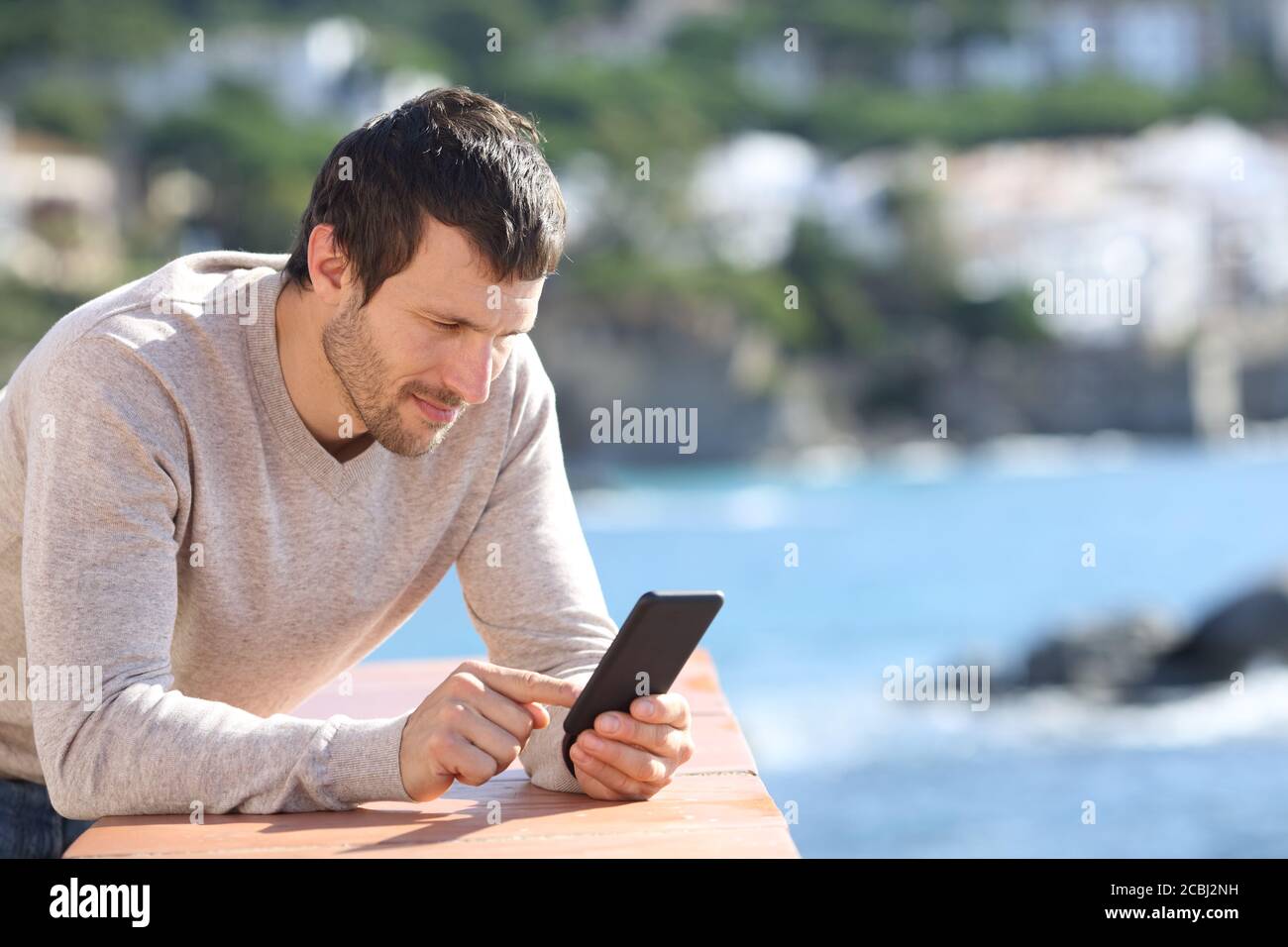 Serious man using smart phone on the beach in spring Stock Photo