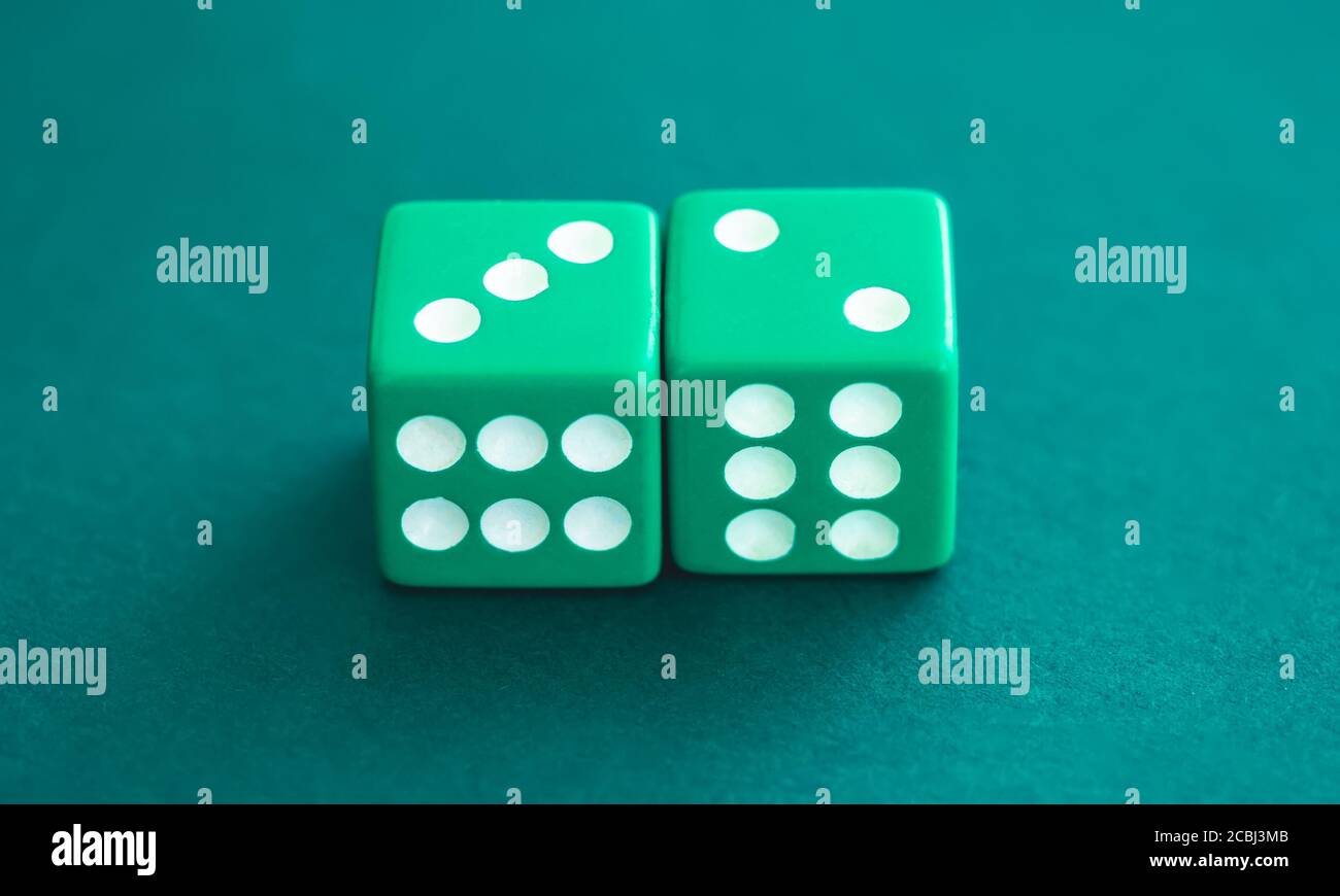 Two green dice on felt background, close up view Stock Photo