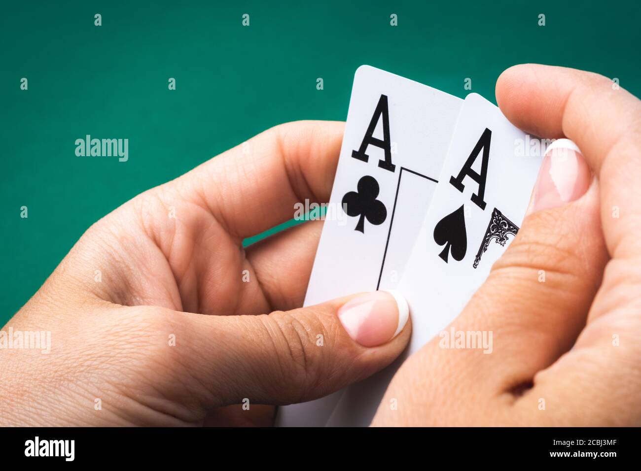 Two aces in girl hand on green felt background, close up view Stock Photo