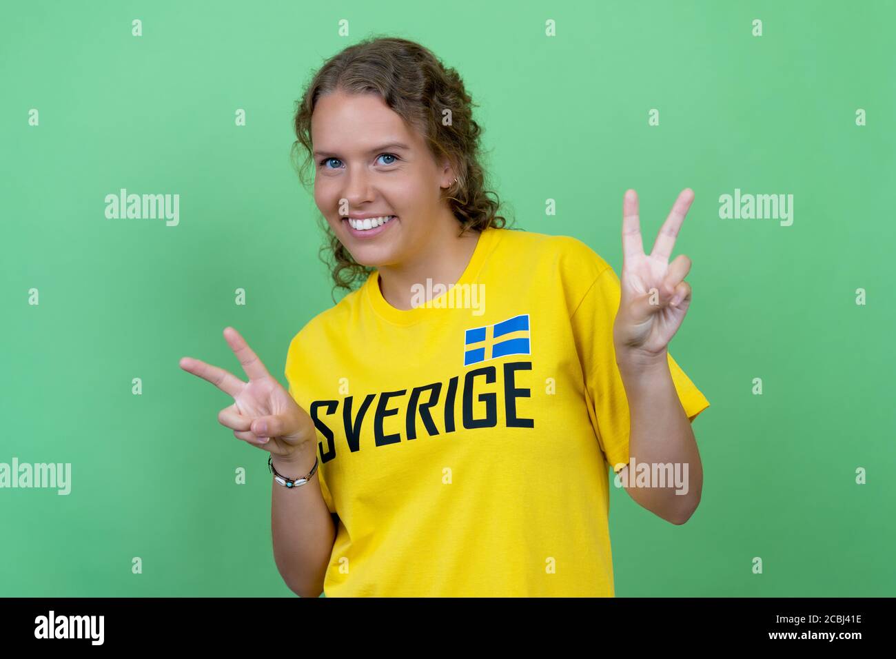 Blond female soccer fan from sweden isolated on green background Stock Photo
