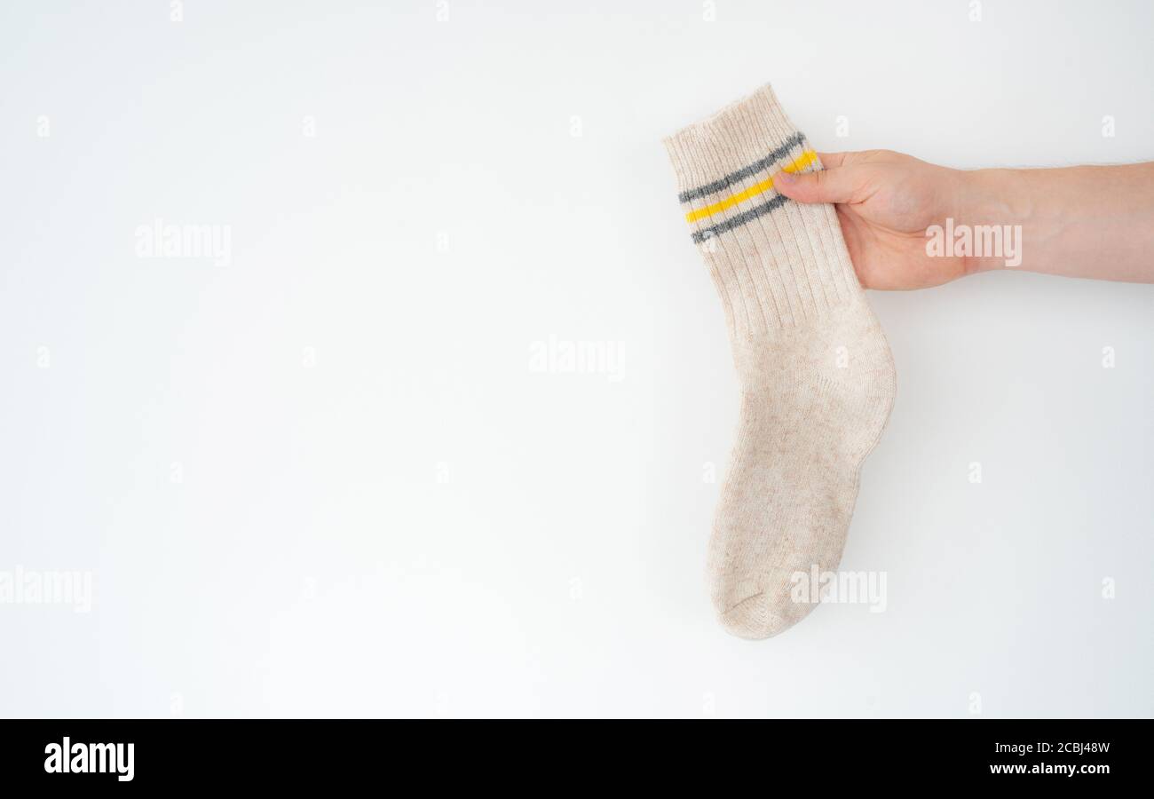 Beige woolen sock in hand on light background Stock Photo