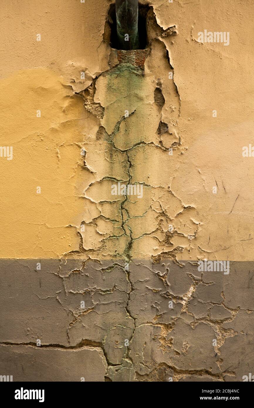 Cracks in old plastered wall. Black hole in wall of retro building or house with cracked plaster. Grunge concept Stock Photo