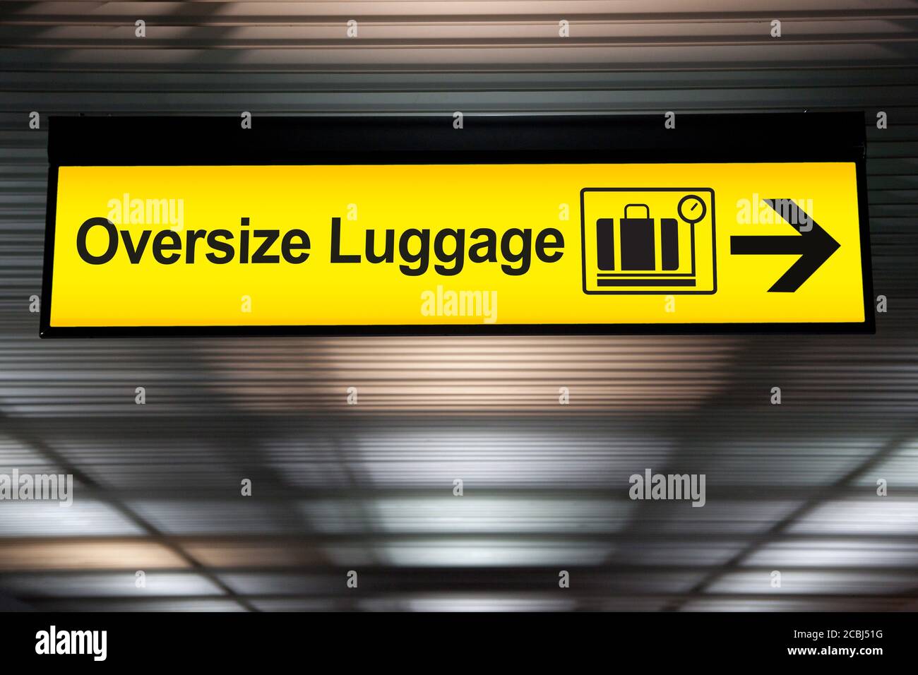 oversize luggage yellow sign with arrow direction hang from ceiling at the airport Stock Photo