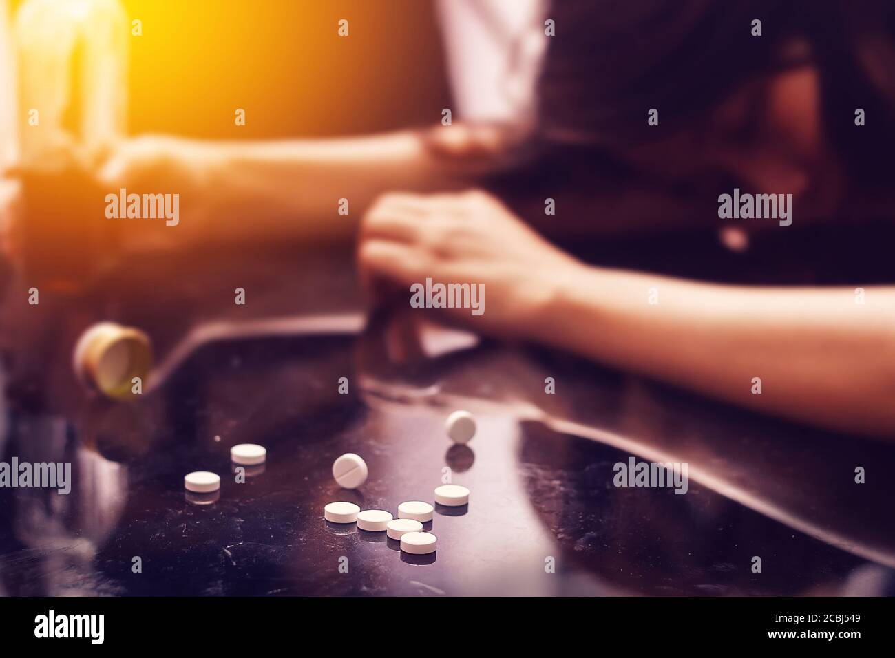 overdose , drug addiction problem concept : Several pill spilled on table Near bottle of alcohol. Stock Photo