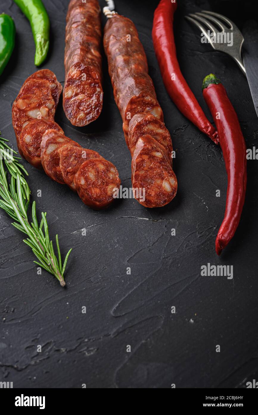 Spanish chorizo sausage slices with herbs and spices on black textured ...