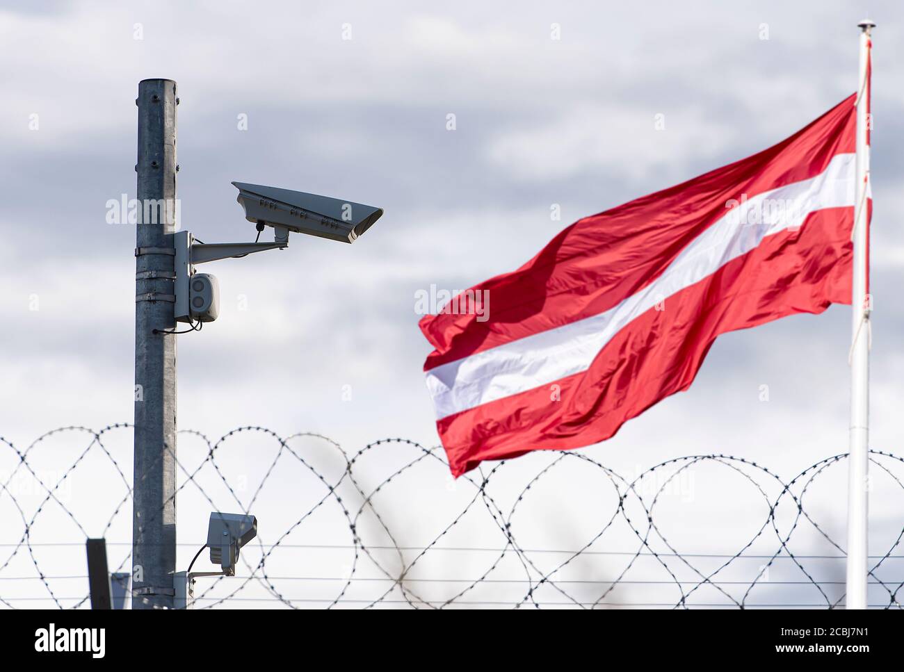 Latvian flag and border with surveillance camera and barbed wire, concept picture Stock Photo
