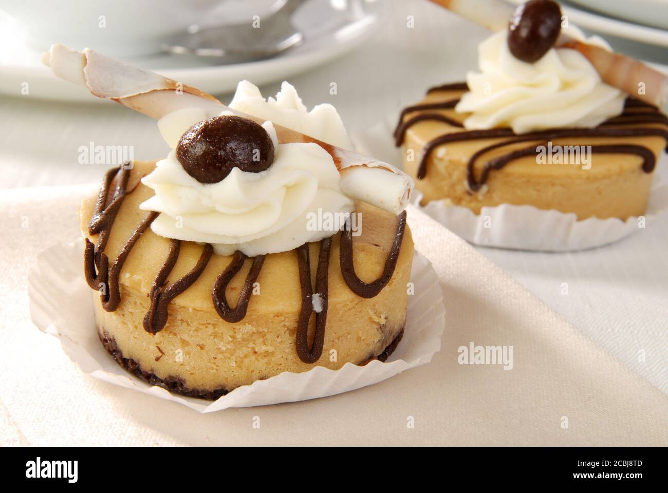 A gourmet mini dessert tart topped with whipped cream and a chocolate covered espresso bean Stock Photo