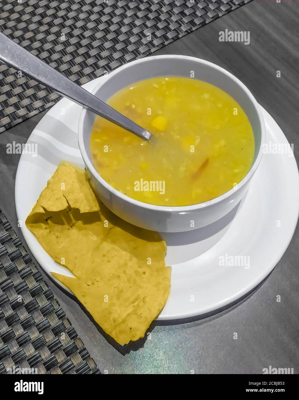 Chicken soup in white bowl on white plate Stock Photo