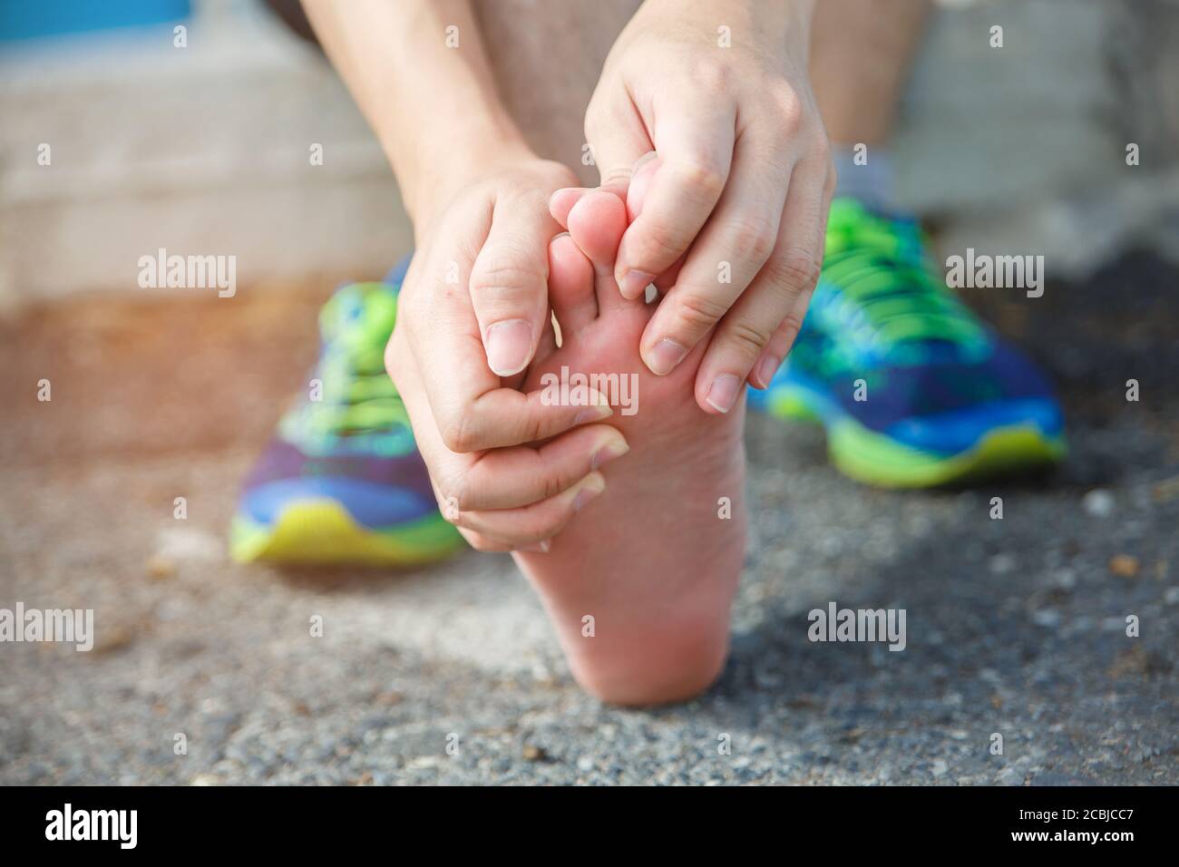 Man runner athlete foot injury and pain. Man suffering from painful foot while running on the road. Stock Photo