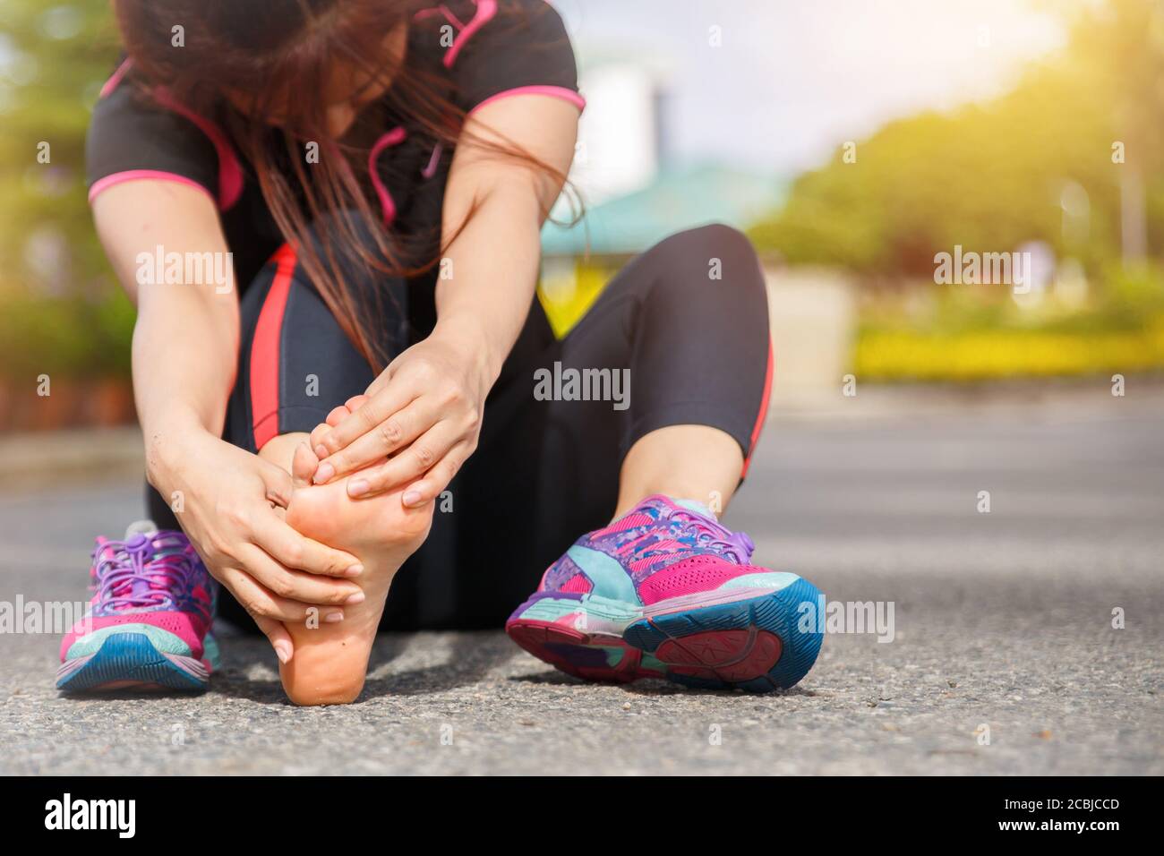 Female runner athlete foot injury and pain. Woman suffering from painful foot while running on the road. Stock Photo