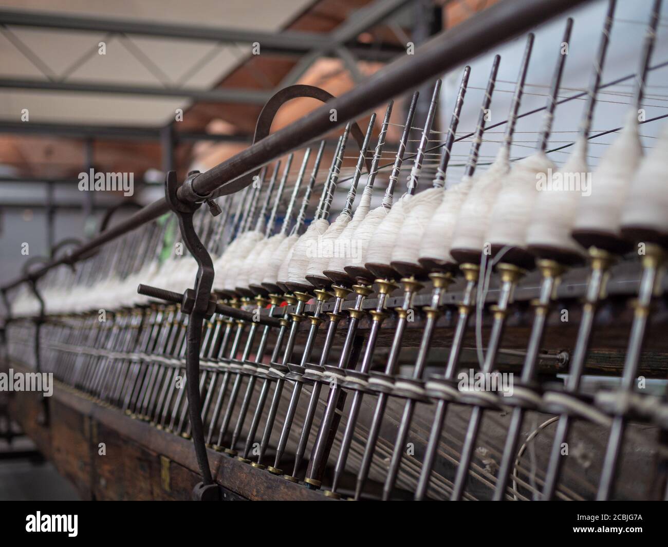 Row of reels with cotton threads ready for the processing on the antigue cotton mill. Steampunk. Stock Photo