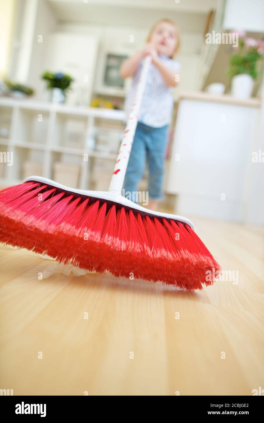 Little child helps sweeping with broom at home Stock Photo Alamy
