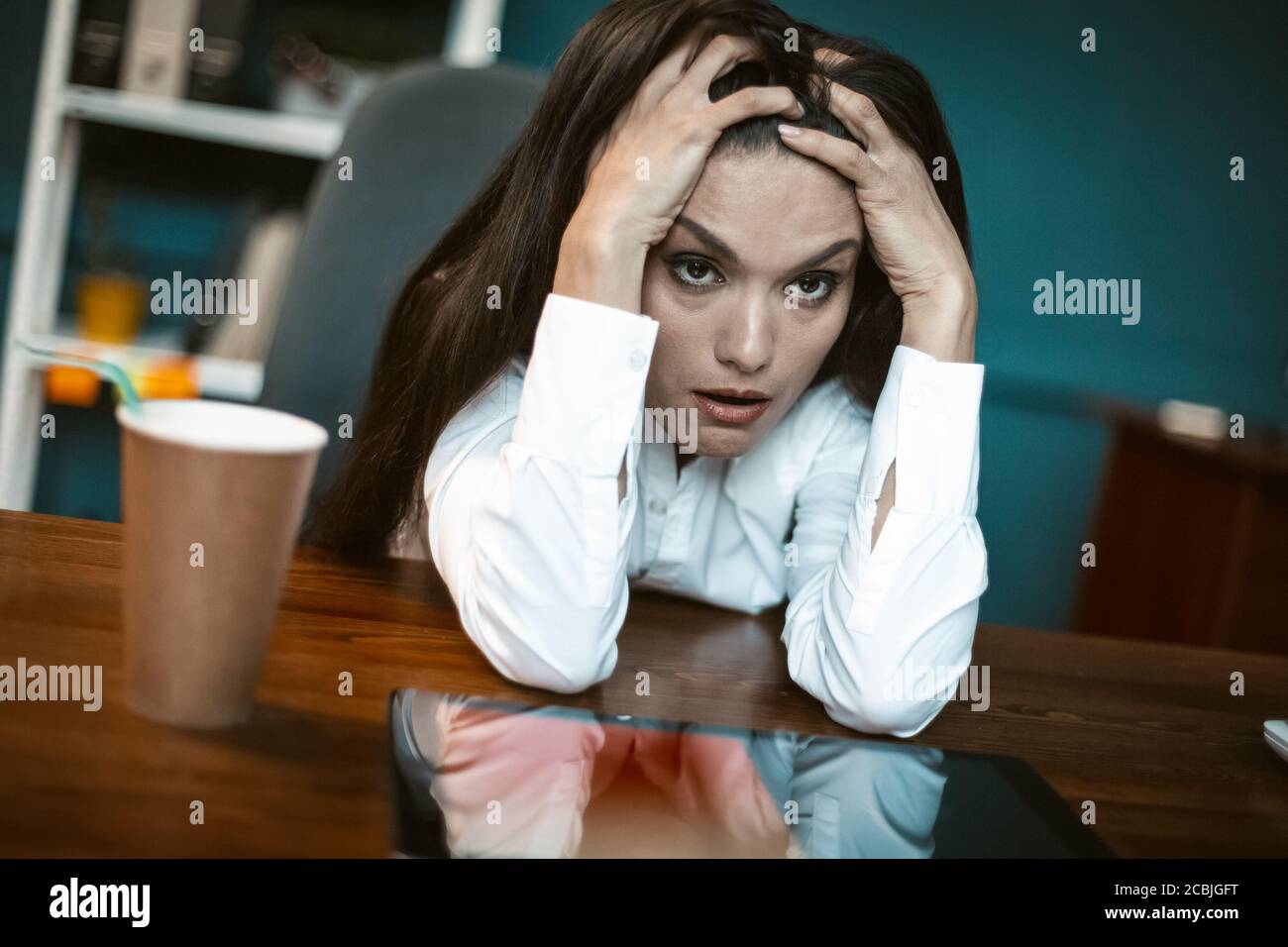 Stressed business woman feels emotional stress. Bored or crazy woman falling into stupor with coffee cup at workplace. Crisis concept. Tinted image Stock Photo