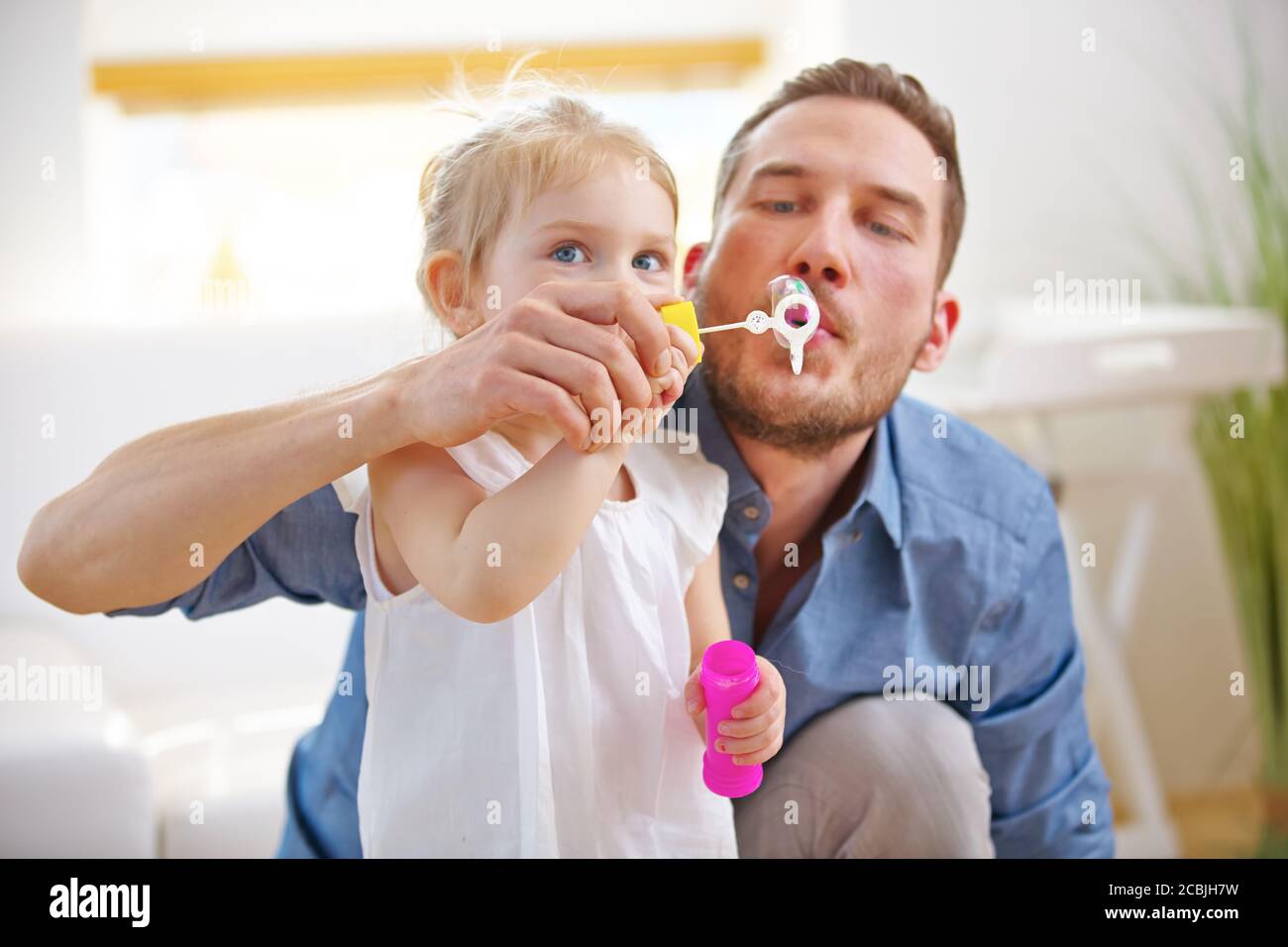 Father and child blow bubbles together at home Stock Photo