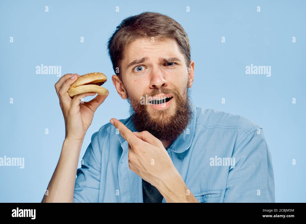 A man with a hamburger in his hands a snack food fast food blue shirt