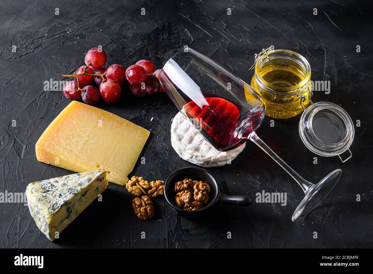 Grapes, red wine, cheeses, honey and nuts side view red merlot wine in