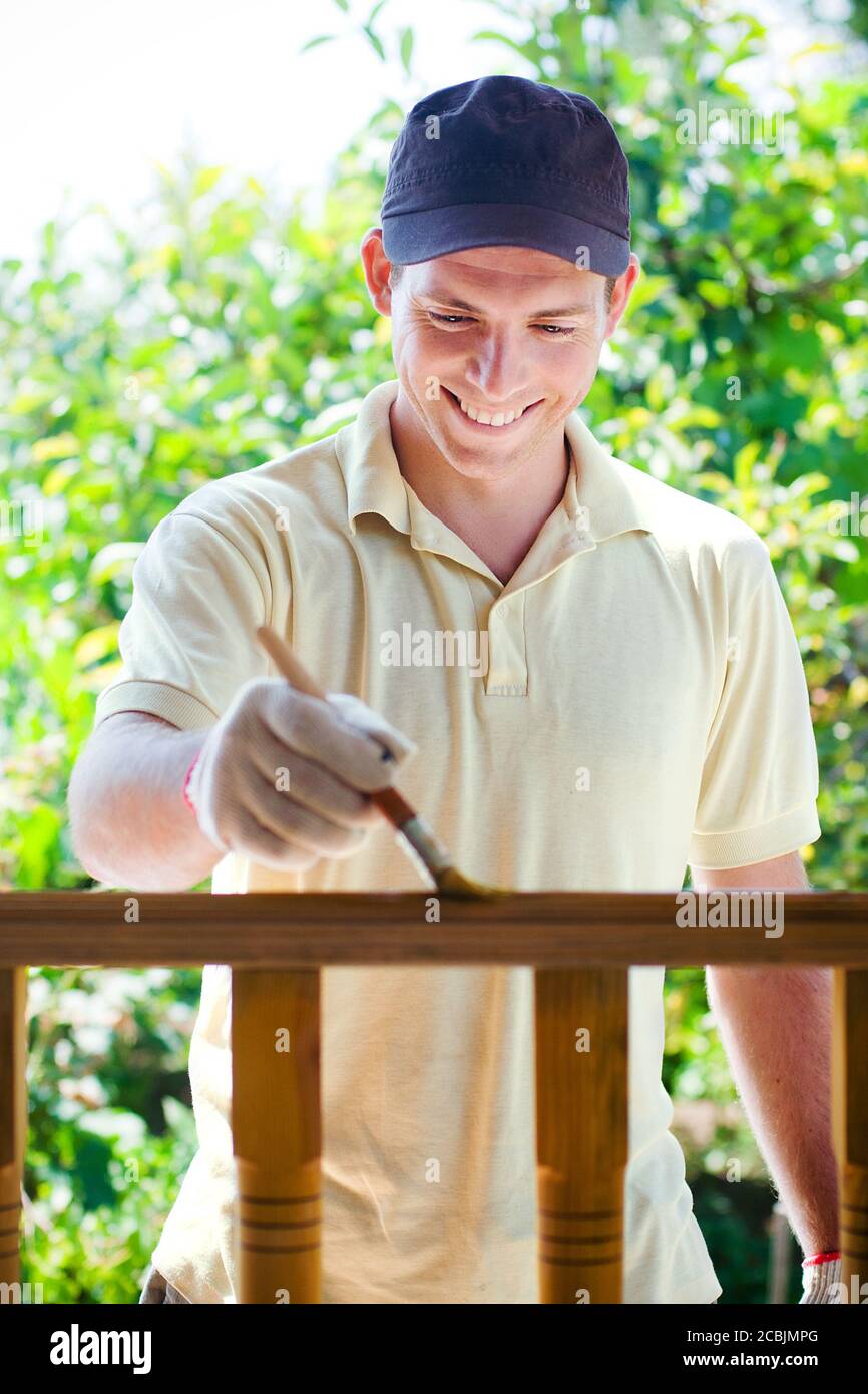 Young man painting wooden fence Stock Photo