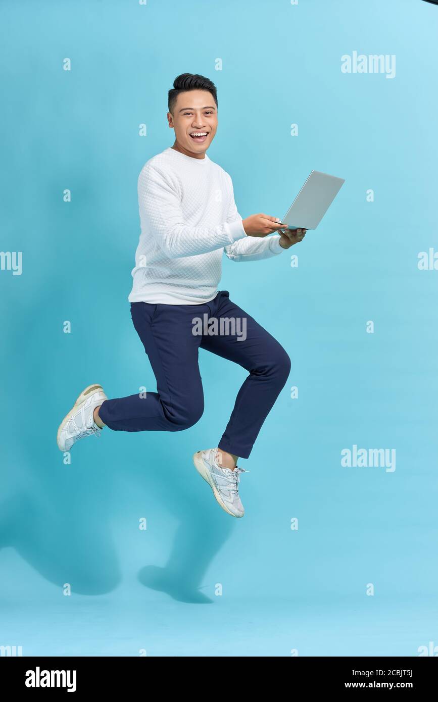 Image of young man dressed standing over blue background using laptop ...
