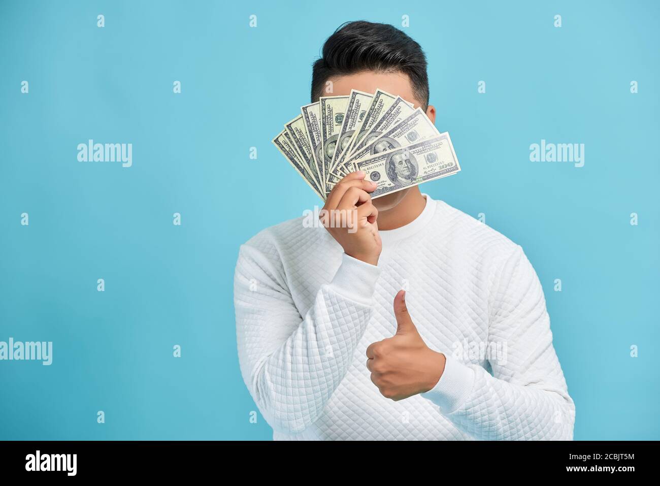 Rich successful businessman holding a wad of cash and giving thumbsup sign. Isolated. Stock Photo