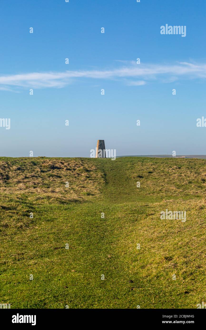 A trig point in the South Downs, with a blue sky overhead Stock Photo
