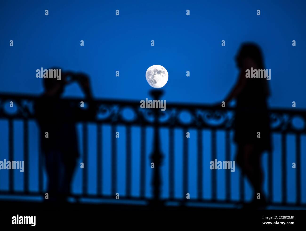 Couple taking pictures under moonling on the Triana bridge, Seville, Spain. Stock Photo