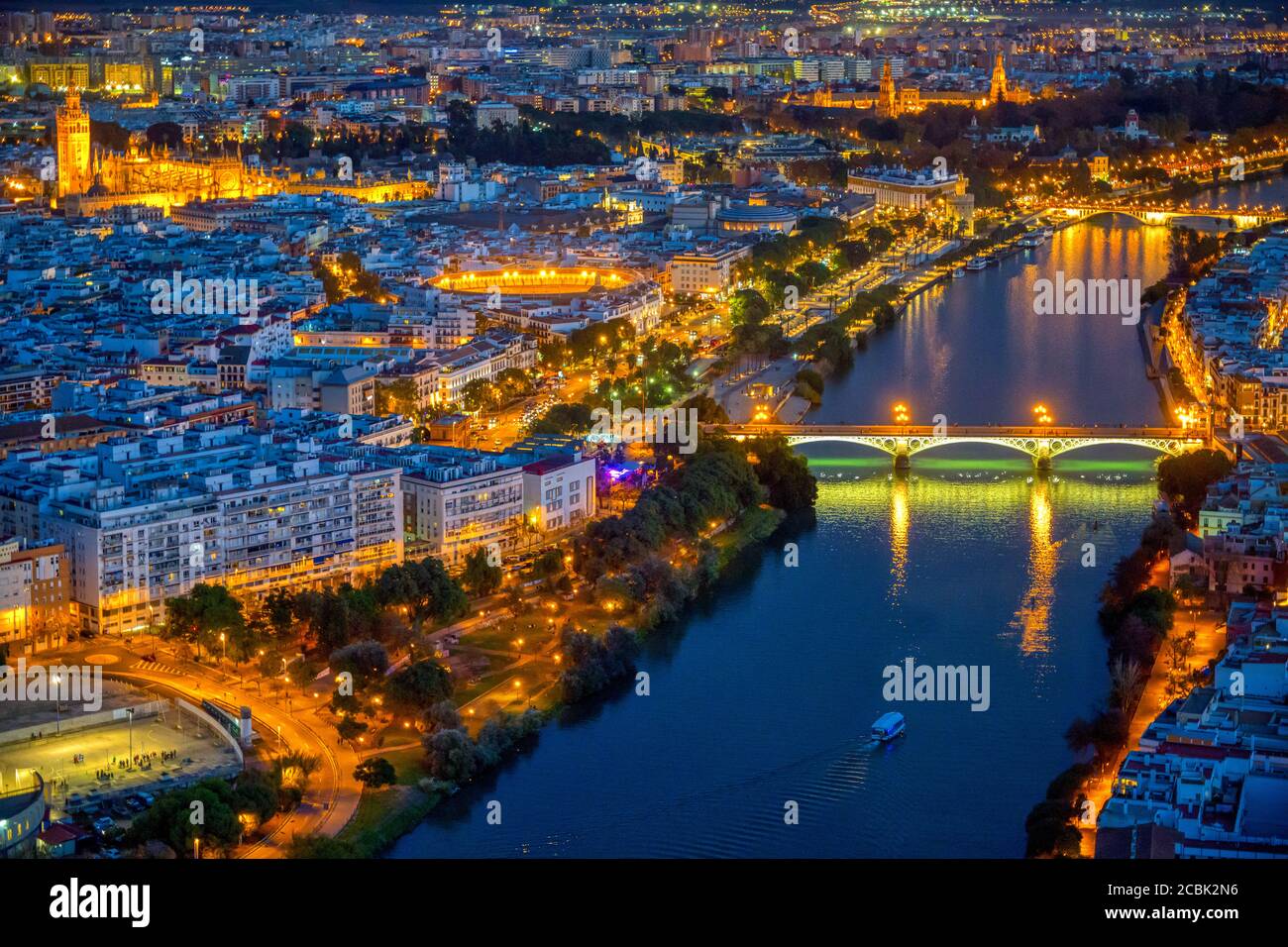 Aerial view of downtown Seville at night, showing some of the main landmarks: Triana bridge, Guadalquivir river, Cathedral, Giralda tower, Maestranza Stock Photo
