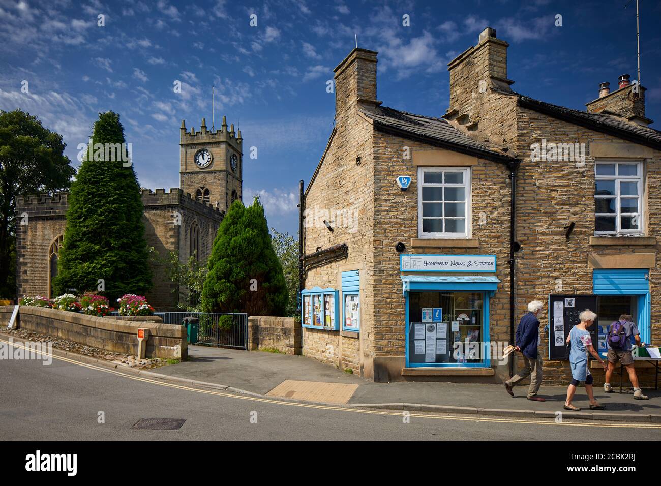 Hayfield village, High Peak, Derbyshire, small shop on Church Street with St Matthews Church Stock Photo