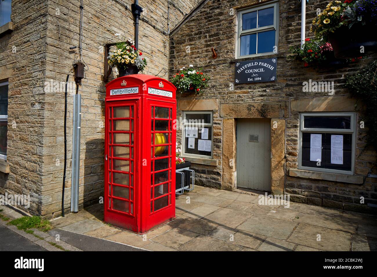 Hayfield village, High Peak, Derbyshire, Parish council building with defibrillator in a old red phonebox on Market Street Stock Photo