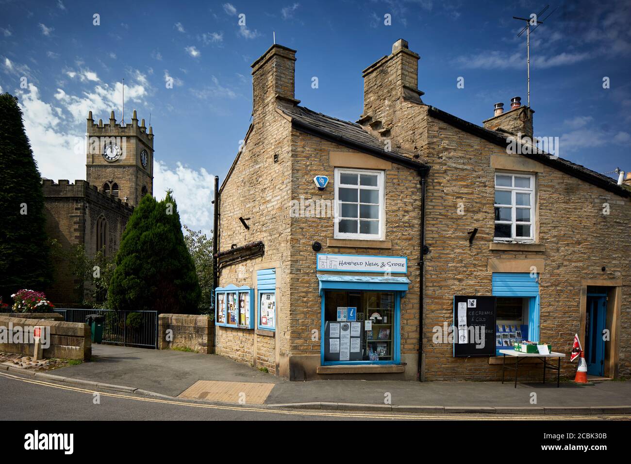 Hayfield village, High Peak, Derbyshire, small shop on Church Street with St Matthews Church Stock Photo