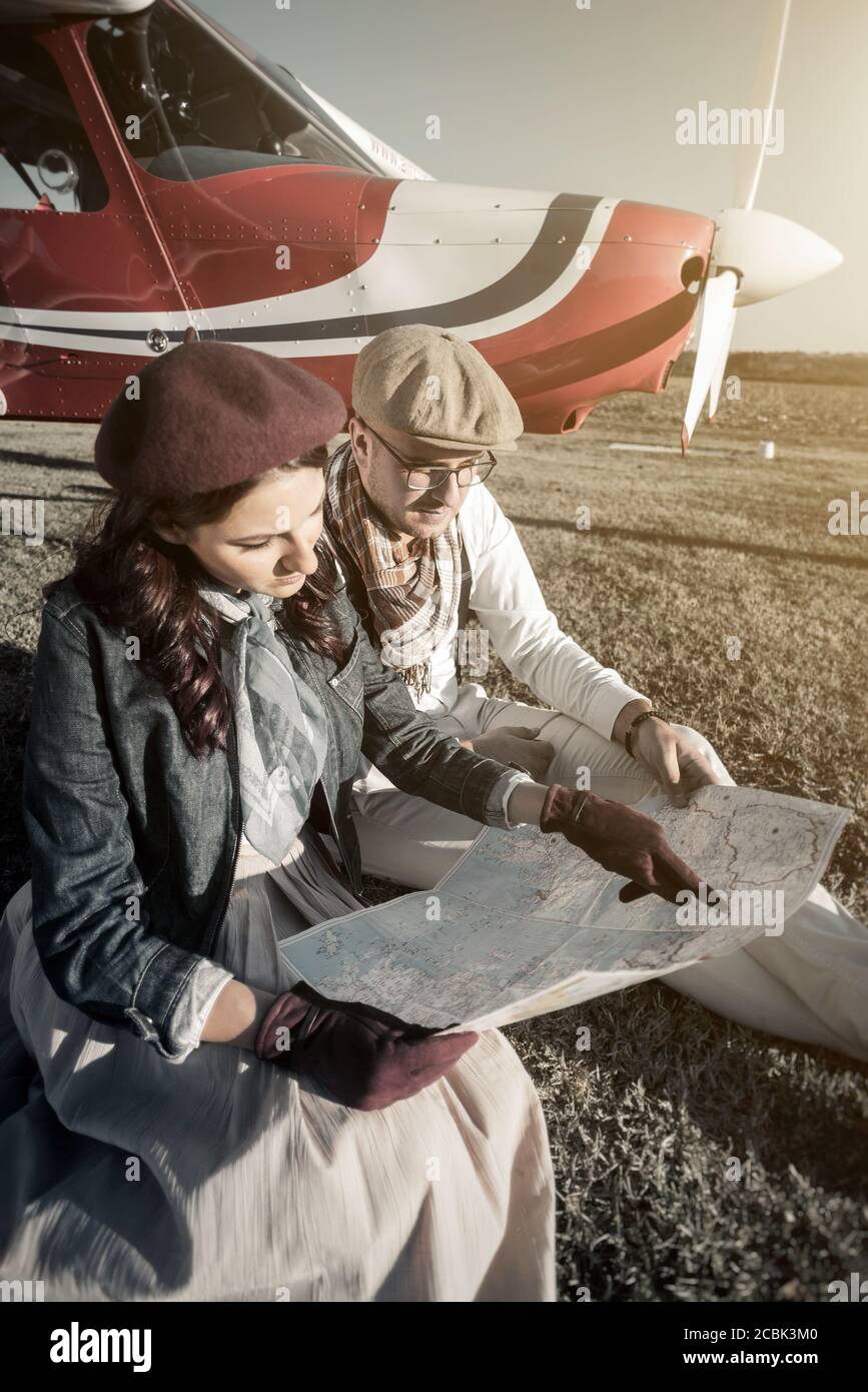 Young couple with private plane looking at map, vertical Stock Photo