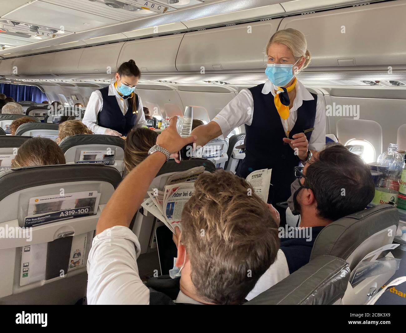 Lisbon, Portugal. 13th Aug, 2020. Flying in times of the coronavirus pandemic, simplified on-board service. Lufthansa stewardess, flight attendant for on-board service, drinks and a cold snack are served, mask compulsory on August 13, 2020. | usage worldwide Credit: dpa/Alamy Live News Stock Photo