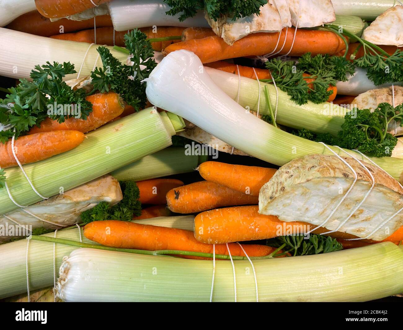 Close up of isolated bundles of fresh raw soup vegetables on german farmer market: leeks, carrots, celery and parsley Stock Photo