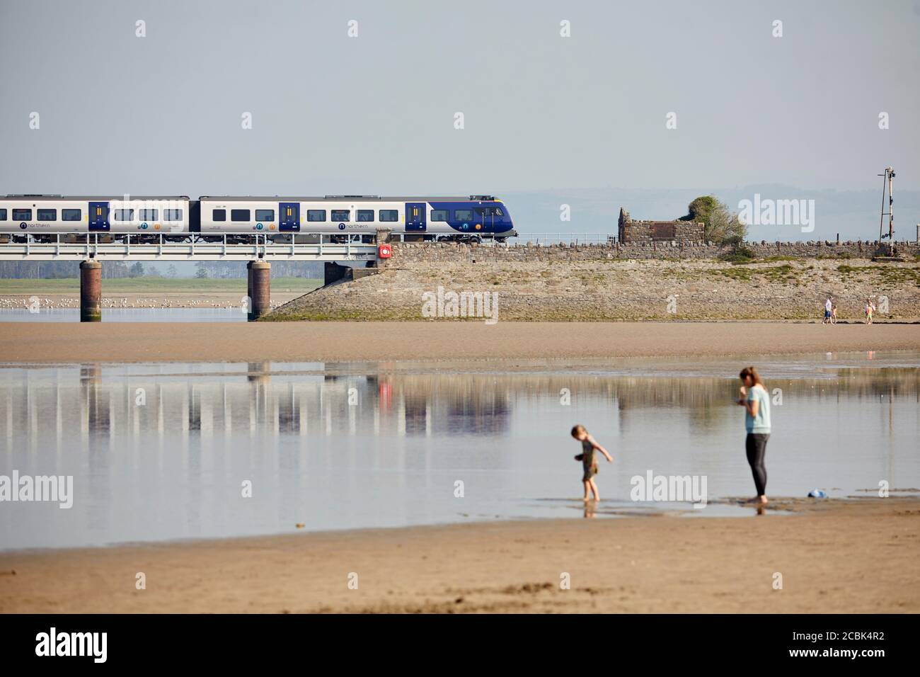 Arnside village Cumbria coastal beach Morecambe Bay,  River Kent crossed by a long viaduct structure carrying the Carnforth and Whitehaven Line over t Stock Photo