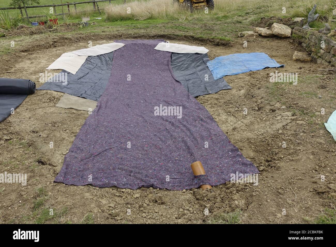 Lining newly dug pond with old carpet and underlay Cotswold UK Stock Photo