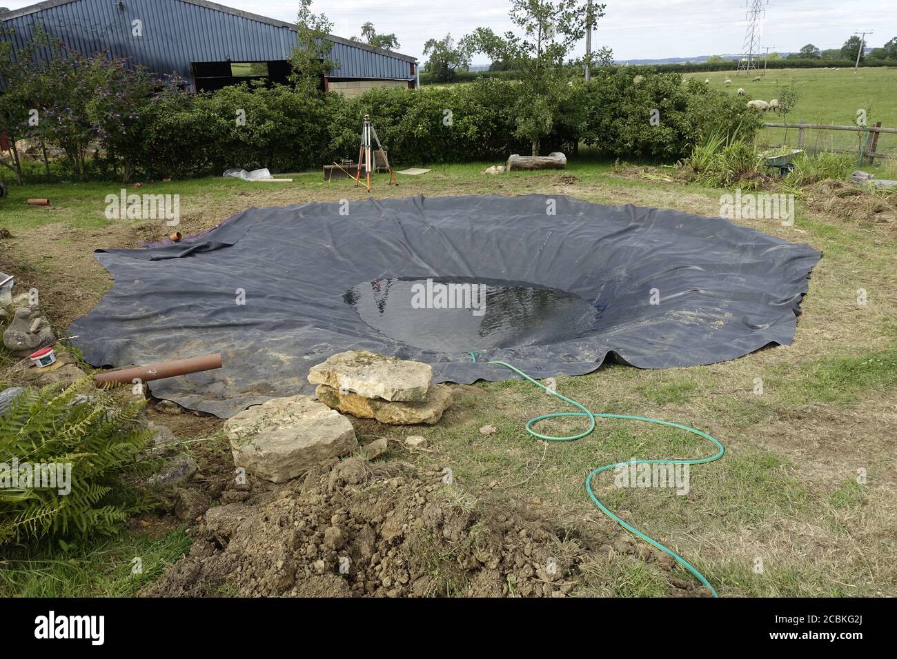 Installing EPDM rubber liner in new pond Cotswolds UK Stock Photo