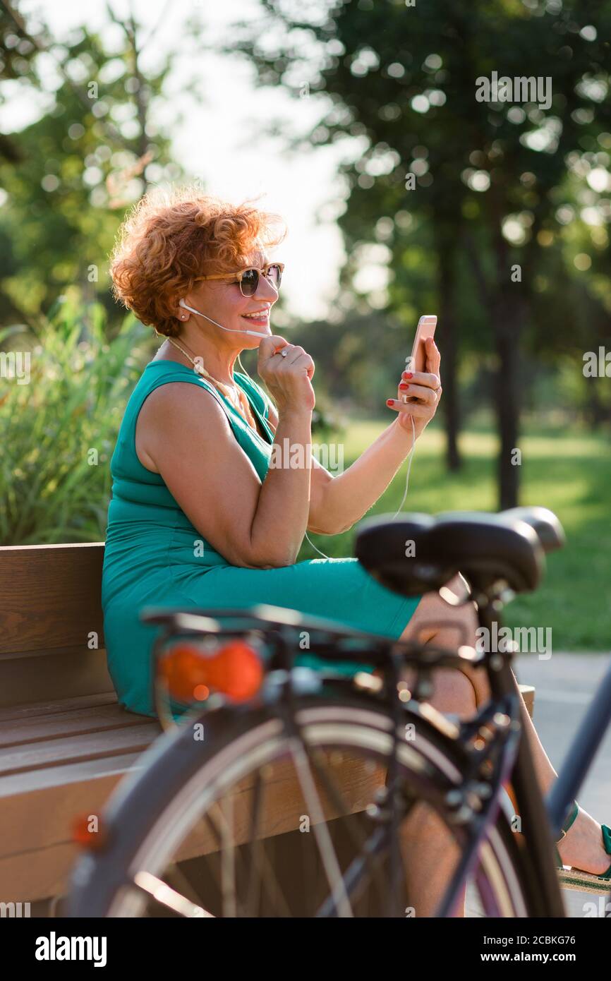 Mature woman using video call on her smartphone in the park Stock Photo