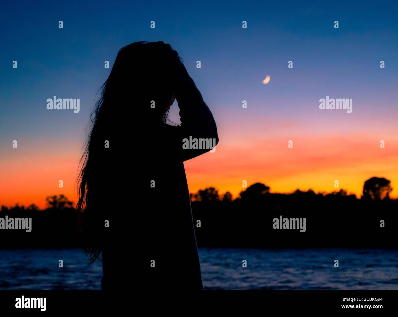 Female silhouette at dusk by the Sacramento River, Northern California Stock Photo