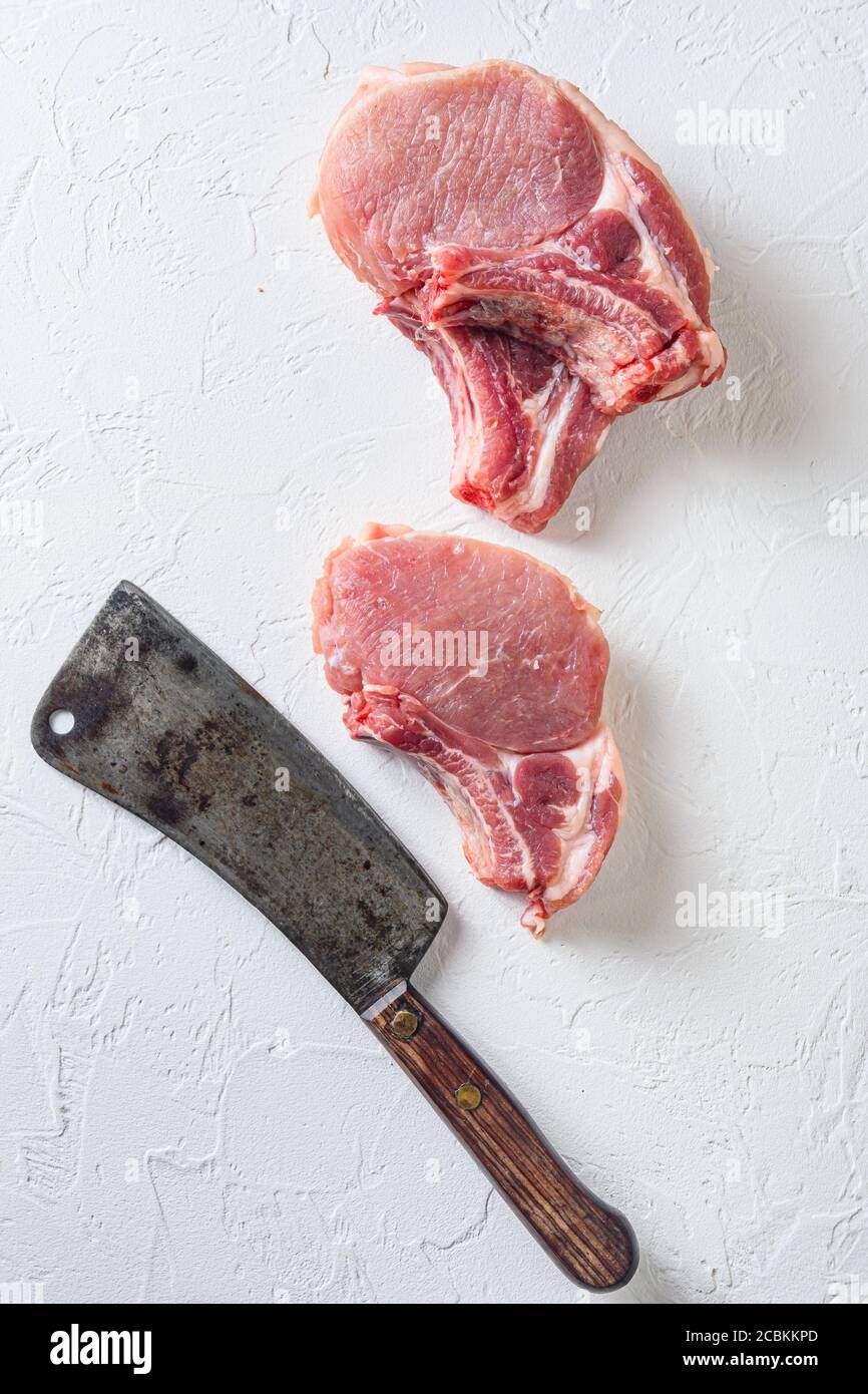 Organic bio Raw pork cutlet , fillets for grilling, baking or frying, Fith butcher cleaver ower textured white background. Overhead view Stock Photo