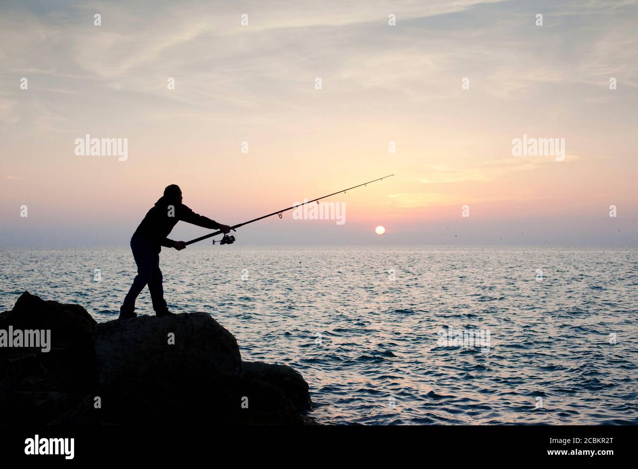 Silhouette of man fishing at sunset Stock Photo - Alamy