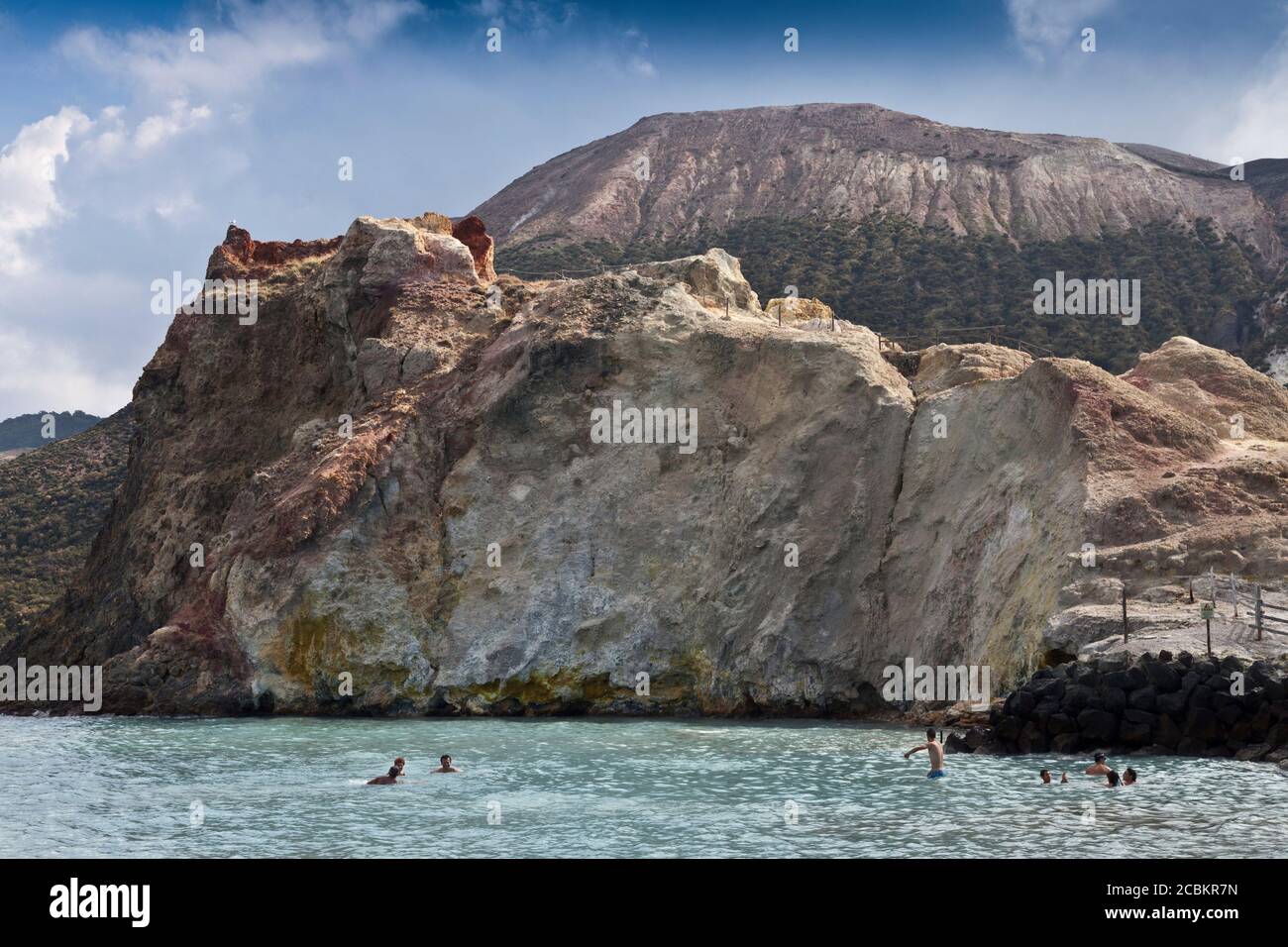 People swimming in ocean by cliffs Stock Photo