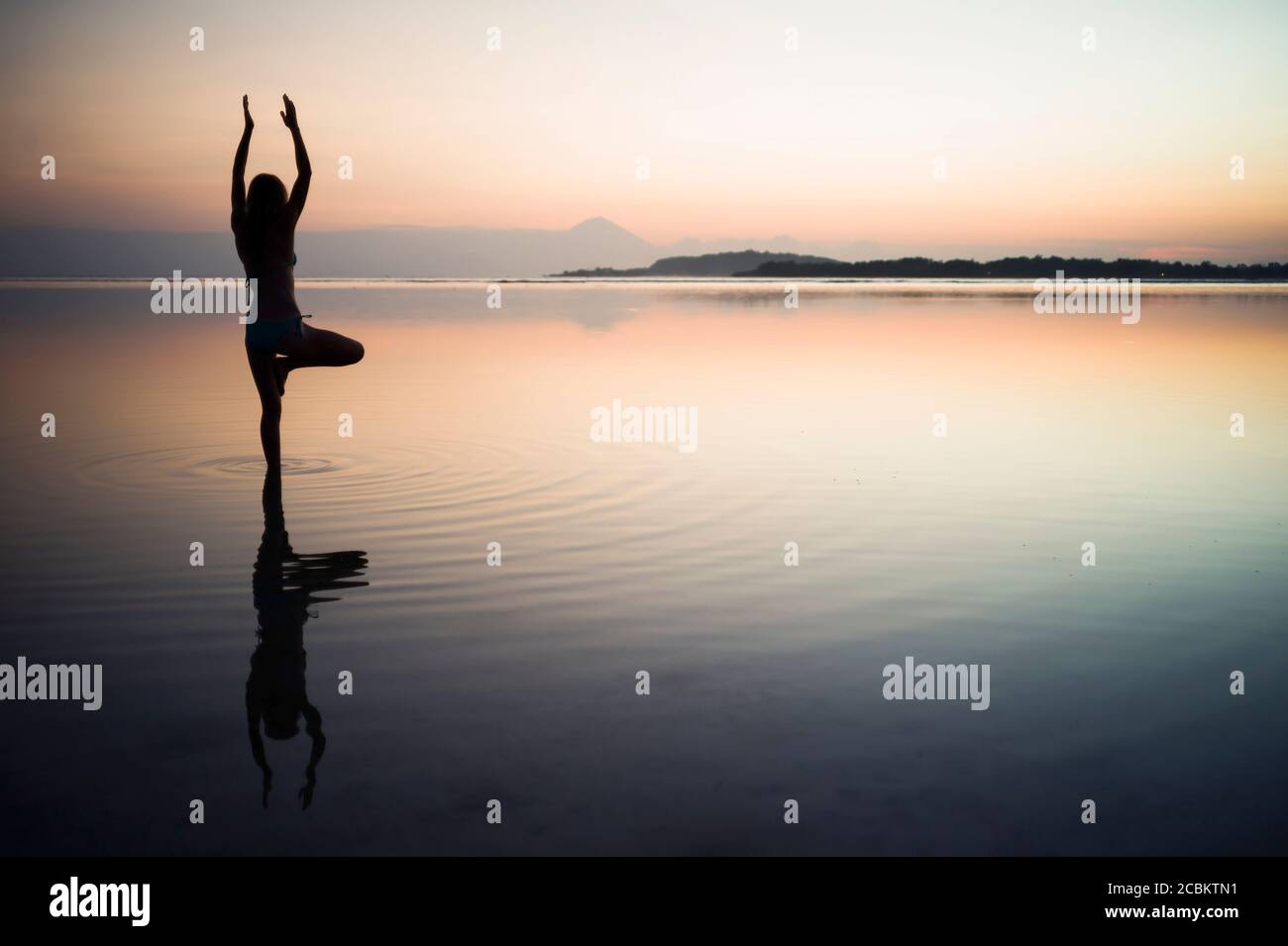 Woman in the sea, in yoga position, rear view, Gili Air, Indonesia Stock Photo